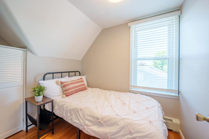 Twin Sized Bedroom (3rd Floor): Includes a closet, fresh linens, twin bed, window shades, mirror, and floor fan.