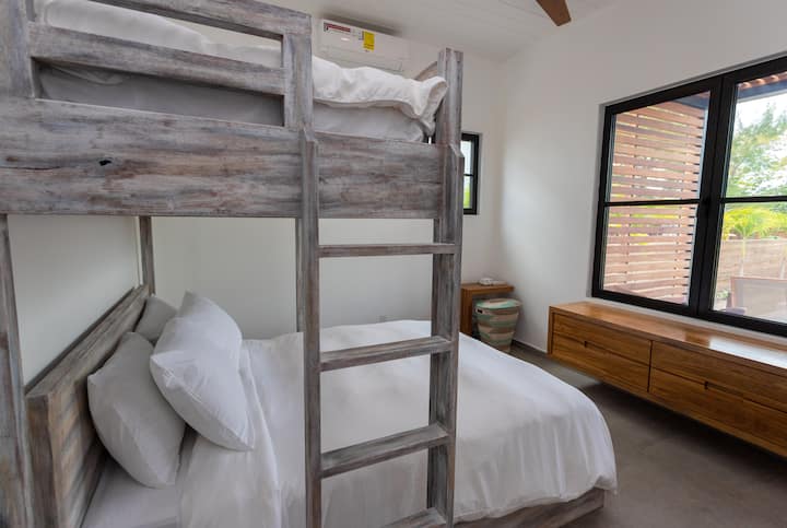 غرفة نوم بمستوى منخفض مع سرير بحجم كوين وطابق واحد ، بالإضافة إلى حمام داخلي