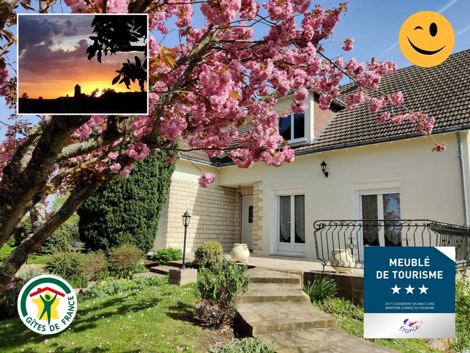 The exterior of the property is framed by blooming cherry blossom trees, providing a vibrant touch. The welcoming entrance is highlighted by large windows and a balcony, with well-kept greenery surrounding the path leading to the front door.