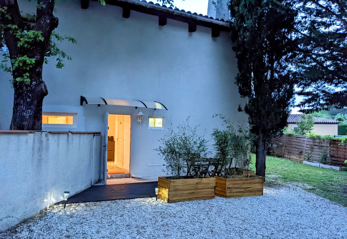 An exterior view of the property showcases a well-maintained entrance under a covered awning. Soft lighting highlights the doorway, leading to a spacious interior. Planters with greenery are positioned near the path, contributing to the serene outdoor setting.