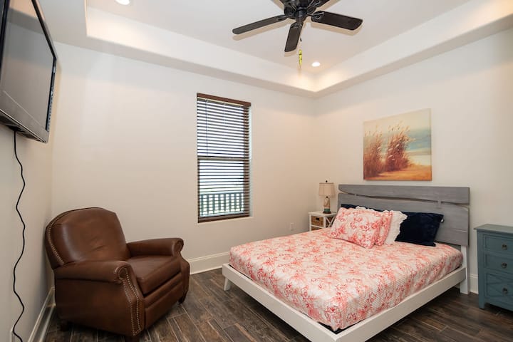 Втора спална соба со брачен кревет, рамен екран и вентилатор на таванот. 