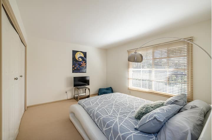 Modrá spálňa s manželskou posteľou a televízorom