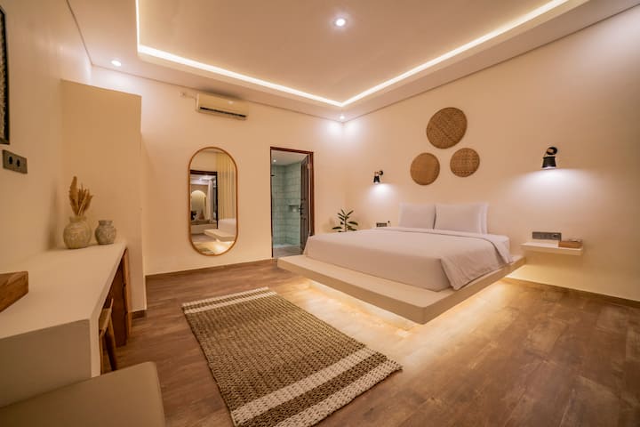 Serene white-themed bedroom w/ soft textures, warm lighting & a relaxing atmosphere
