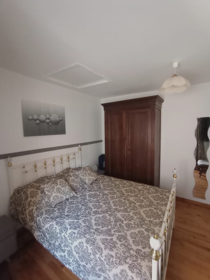 сива спална соба со два пристапа, една директно на балкон и скали надвор и една одвнатре