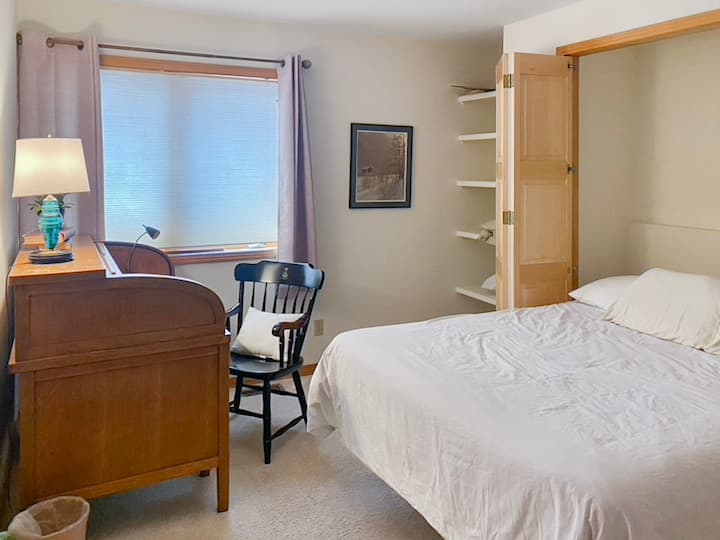 Derde slaapkamer met een queensize bed en een groot roll-top bureau.