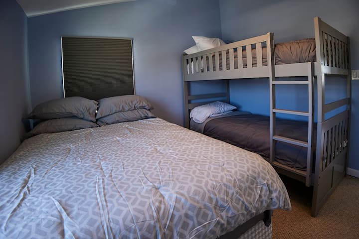 Segundo dormitorio con cama tamaño queen y dos camas individuales sobre literas individuales.