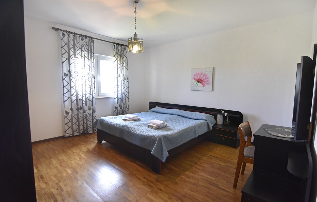 ห้องนอน 1 พร้อมเตียงคู่โต๊ะข้างเตียง 2 ตัวพร้อมโคมไฟกลางคืนและโต๊ะทำงาน