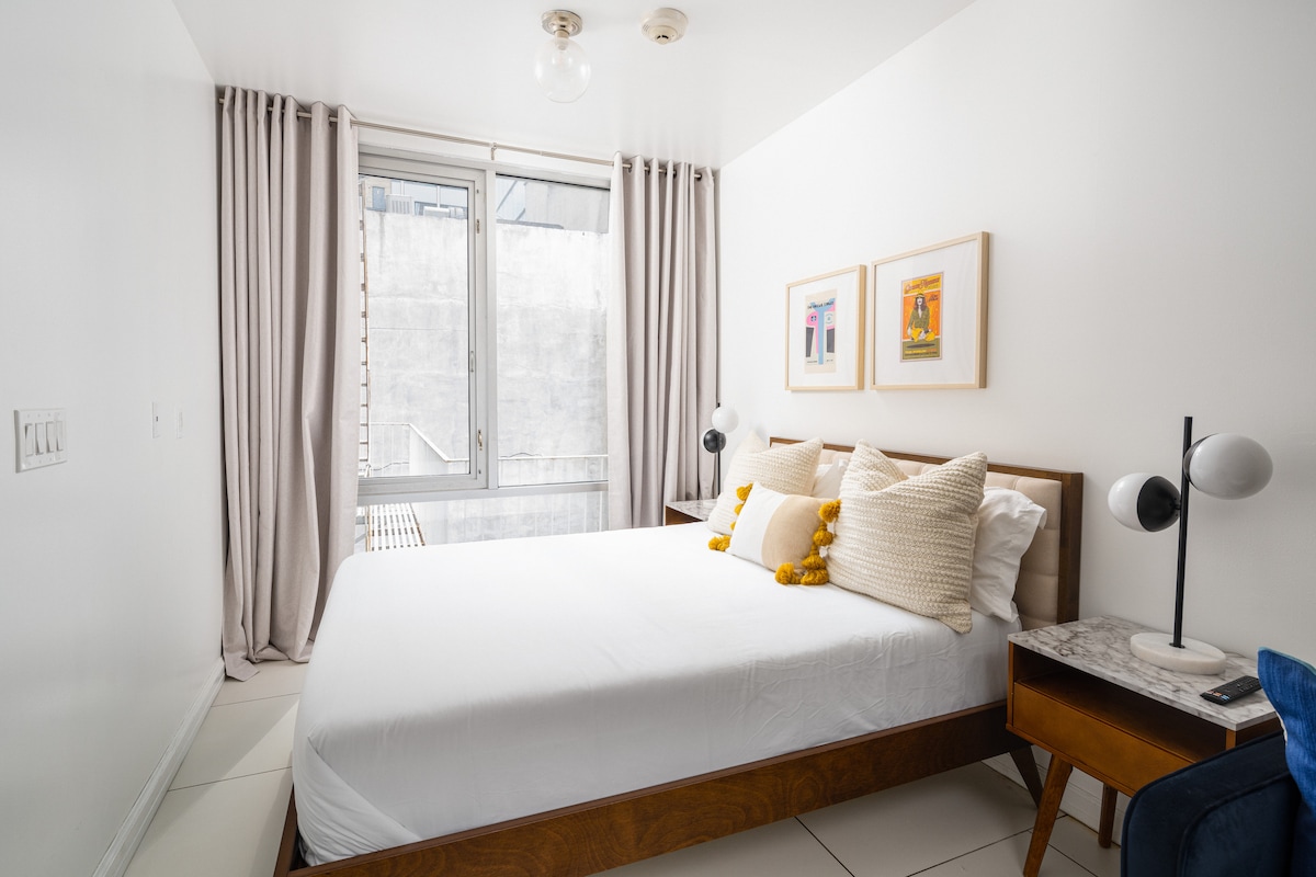Queen bed beside the window with a bedside table
