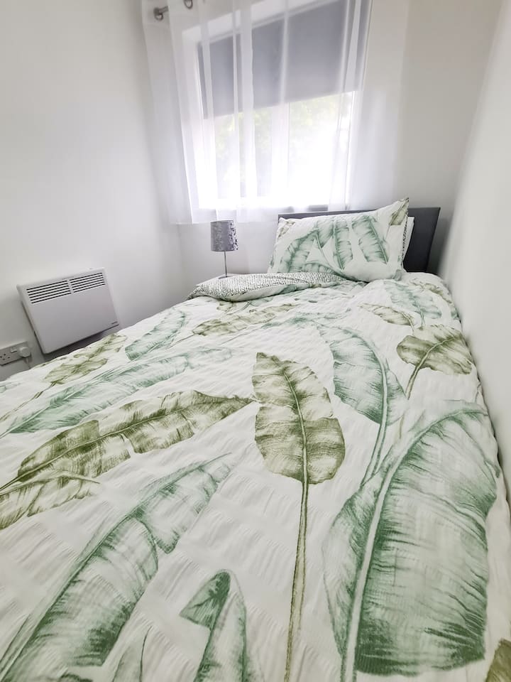 Dhomë gjumi teke me krevat të rehatshëm, gardërobë, qoshe të errët, dollap pranë krevatit dhe ngrohje