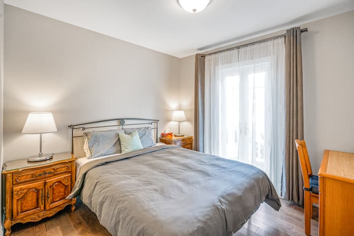 Guest bedroom with queen size bed, clean linens, closet, desk, bedside lighting. 