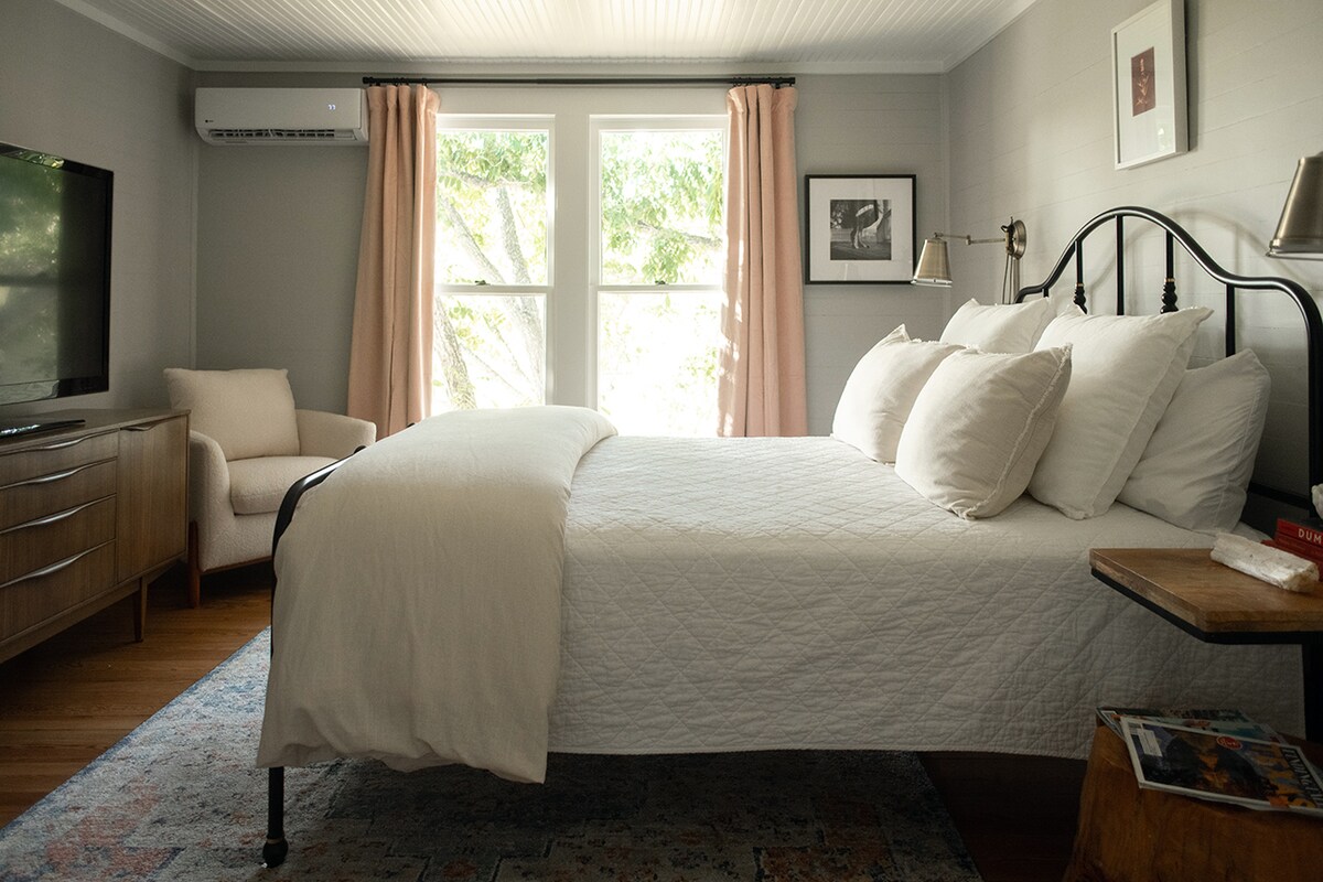 The second guest bedroom located on upper floor is filled with warm shades of pink, original photographs and a large screen tv, is perfectly situated across the hall from its own private full bath. 