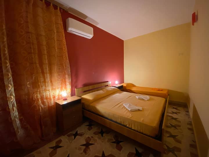 Tweede 'ORANJE' slaapkamer met een tweepersoonsbed, een eenpersoonsbed en airconditioning