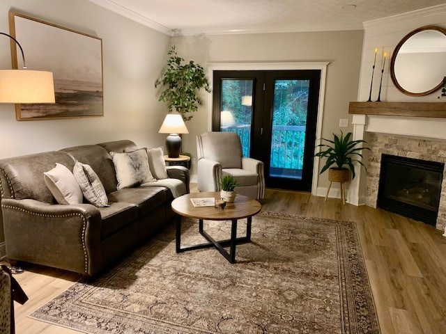 A cozy living area is furnished with a dark sofa and a recliner, complemented by a round coffee table. A stone fireplace is situated against the wall, while a large mirror enhances the space. Natural light enters through glass doors leading to a balcony.