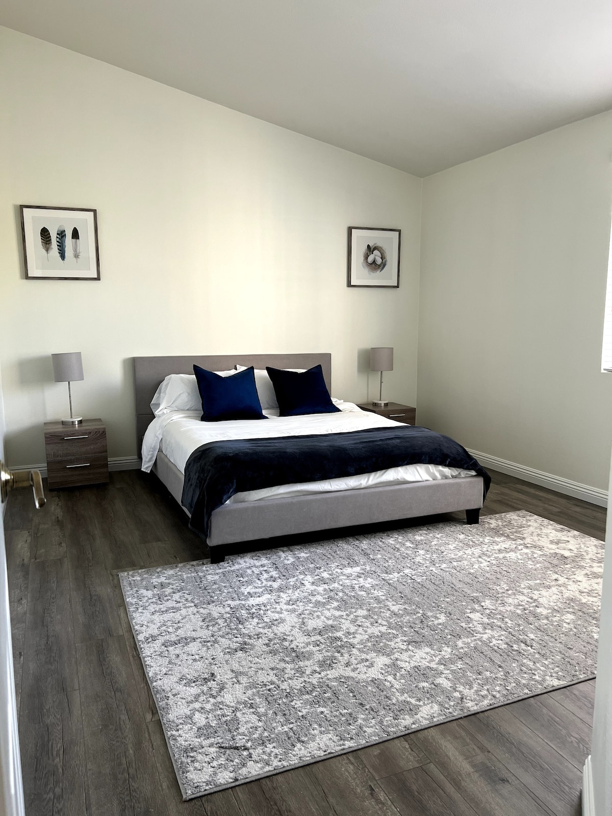 Pumzika katika chumba hiki cha kulala cha starehe na kitanda cha malkia na mfariji mweupe. Imepambwa na mchoro uliochochewa na mazingira ya asili na mwangaza wa hali ya juu, sehemu hii ya utulivu inakaribisha mapumziko na ukarabati. Ubunifu wa minimalist na mpango wa rangi ya muted huunda mazingira ya amani