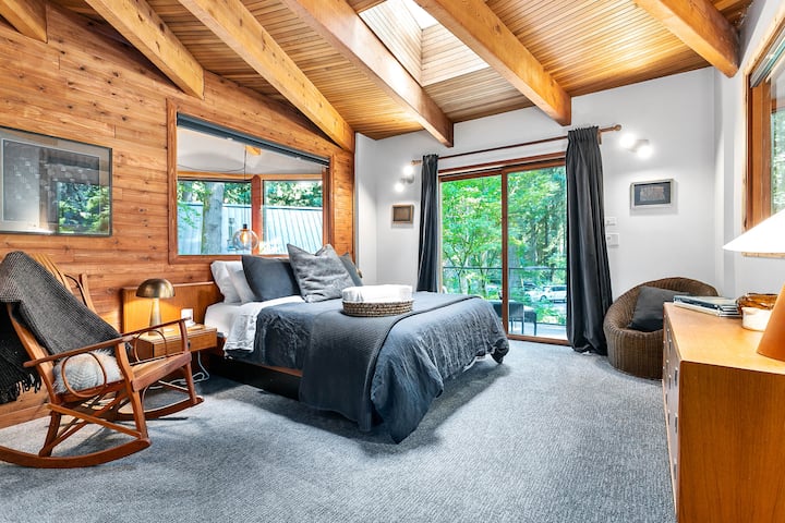 The primary bedroom overlooks the first floor living space through large windows, and has a private deck with a lounge chair
