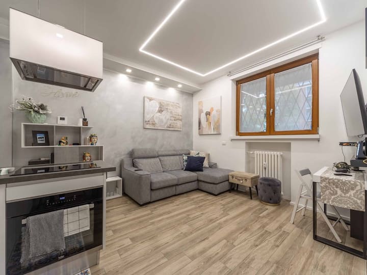 Sala de estar con gran pantalla de TV. Sofá triple, mesa con cuatro asientos.