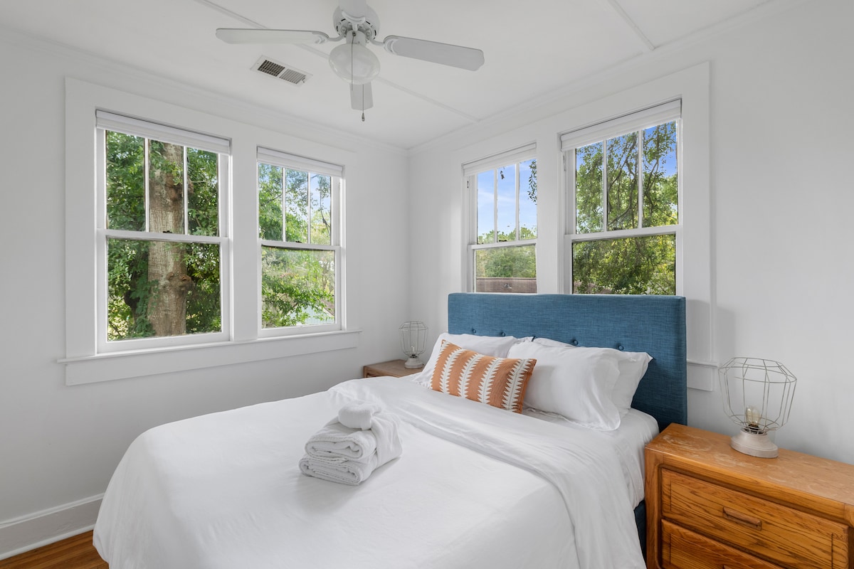 The bedroom in the upstairs apartment has a queen-sized bed with tree-top views