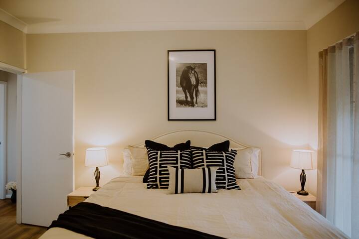 Bedroom 1 features a king bed in stylish black and tan colours. Champion racehorse, 'Desert War', bred and trained at Gooree Park watches over you.
