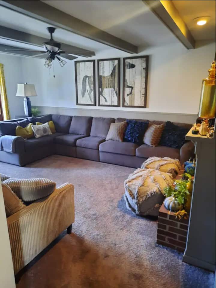 Acogedora habitación familiar justo al lado de la cocina con cama extraíble, chimenea de gas de trabajo y TV grande. Puertas francesas hacia la terraza grande y cercas en el patio con equipo de juego.