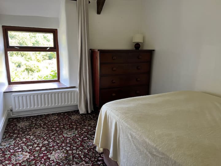 ห้องนอนที่ 2 อยู่ด้านบนของบันไดมีเตียงคู่และวิวสวน