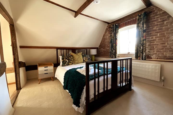 Спалнята „Горчица“ с двойно легло и тухлена стена.