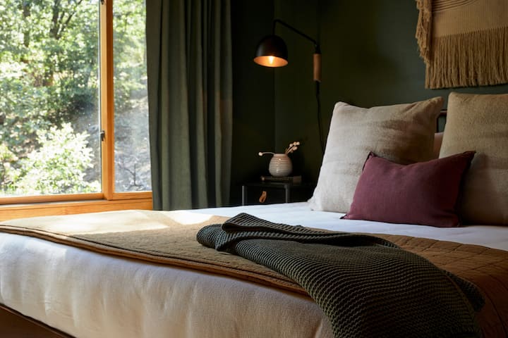 Cozy, curated bedroom details. The King bedroom features unobstructed forest views and en suite bathroom with stand-up shower,  Article bed, Casper mattress, Loftie alarm clock, and more. 