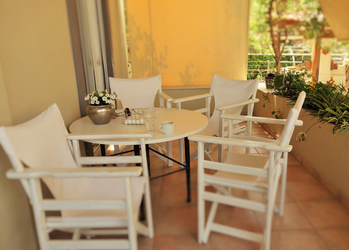 A comfortable outdoor seating area features a round table surrounded by four white chairs. potted plants add greenery to the space, enhancing the inviting atmosphere perfect for relaxation or dining al fresco.