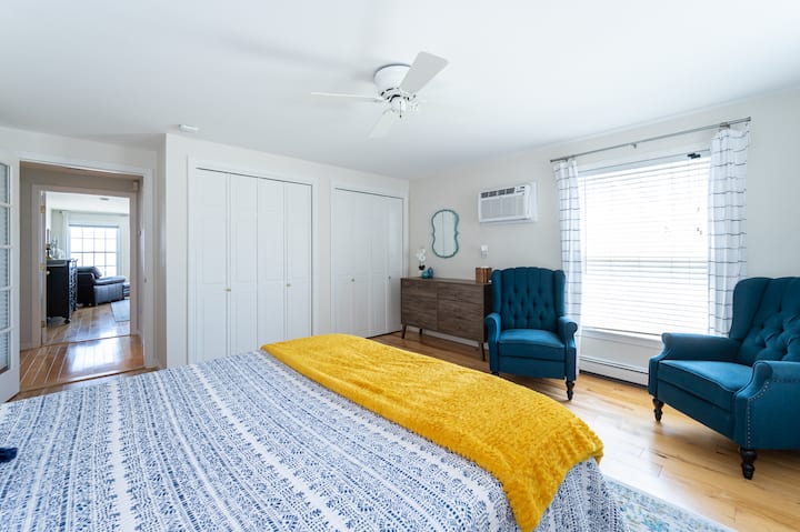 Dormitorio con vistas al jardín del primer piso (cama tamaño queen) con dos sillas reclinables, unidad de aire acondicionado de pared