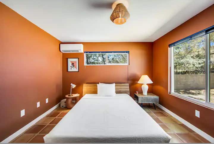 Chumba hiki cha kulala cha terra cotta kina kitanda aina ya queen, mwanga wa jua mwingi na dawati la uandishi. 