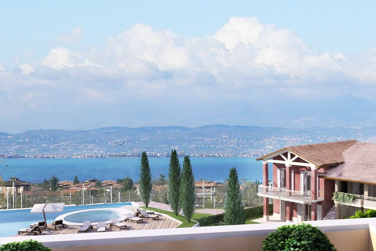 A scenic view showcases a modern residence with a spacious pool area. Lush green trees frame the foreground, while the sparkling blue lake is visible in the background, under a partly cloudy sky. The tranquil atmosphere reflects a serene holiday environment.