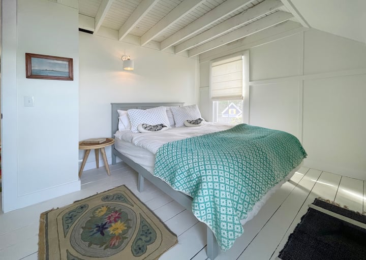 快適なマットレス、プレミアムリネン、ユニークなアート作品を備えた寝室。