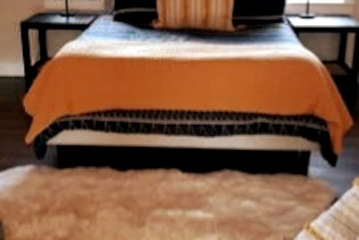 Dormitorio tipo loft con una acogedora cama tamaño queen, sábanas en capas y detalles cálidos, una de las dos acogedoras camas en el espacio abierto del loft.