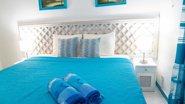 King-size bed at Sea Horse Apartment The Sunset Sands. This one of our 4 1-bedroom apartments in Speightstown, St. Peter Barbados. Just look out the window and enjoy the view of the garden and gabezo.