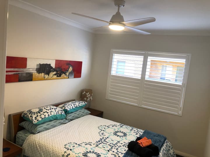 Amplio segundo dormitorio con cama tamaño queen, colchón cómodo y empotrado. Persianas de plantación con ventilador de techo de calidad.