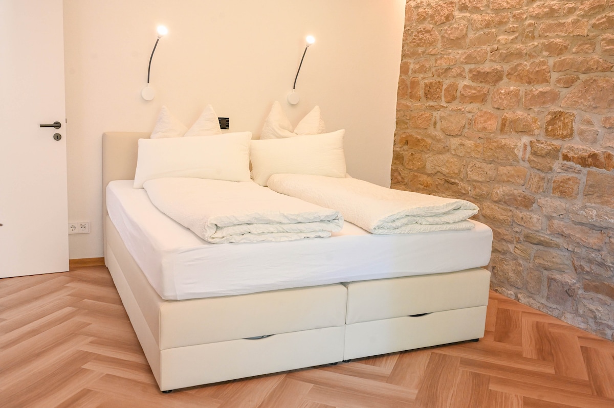 Large box spring bed by Welcon. Outlets left and right with USB-A and USB-C connection for charging phones.