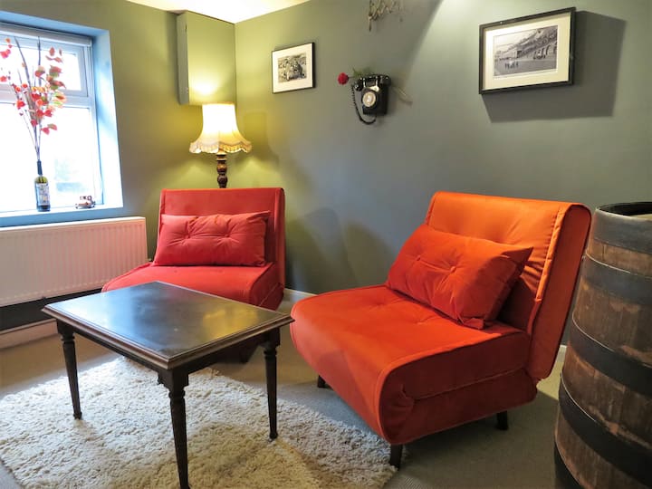 PUB SNUG
Lower ground second living room.
vitanda vya kiti VILIVYOTENGENEZWA vinaweza kuchukua wageni wawili wa ziada katika eneo hili la jumuiya. 
Vitabu na michezo kwa watu wazima na watoto.
Kiti kidogo cha Poang