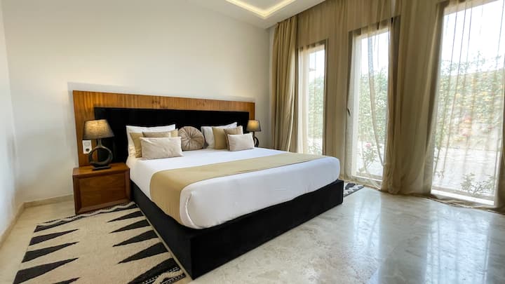 חדר השינה השני בצידו השמאלי של הווילה הענבר, פשוט ופיכח, עם טלוויזיה חכמה וחדר רחצה פרטי.