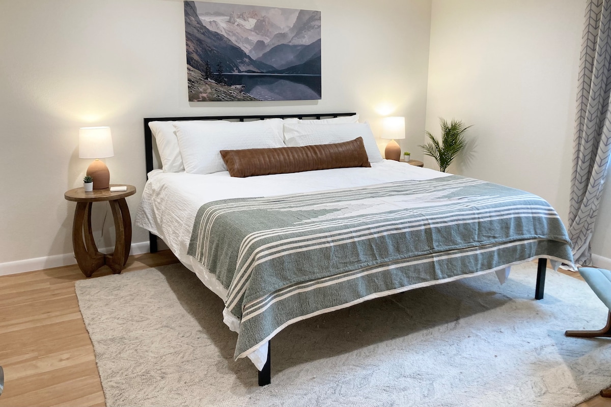 Dhomë dopio "king" me detaje të qeta, duke përfshirë një batanije të thurur me dorë, abazhurë terrakote dhe perde të errëta 