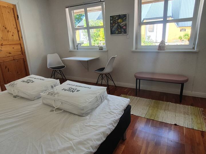 Kitanda cha watu wawili na sehemu ya kulia chakula karibu na dirisha linaloangalia ua.