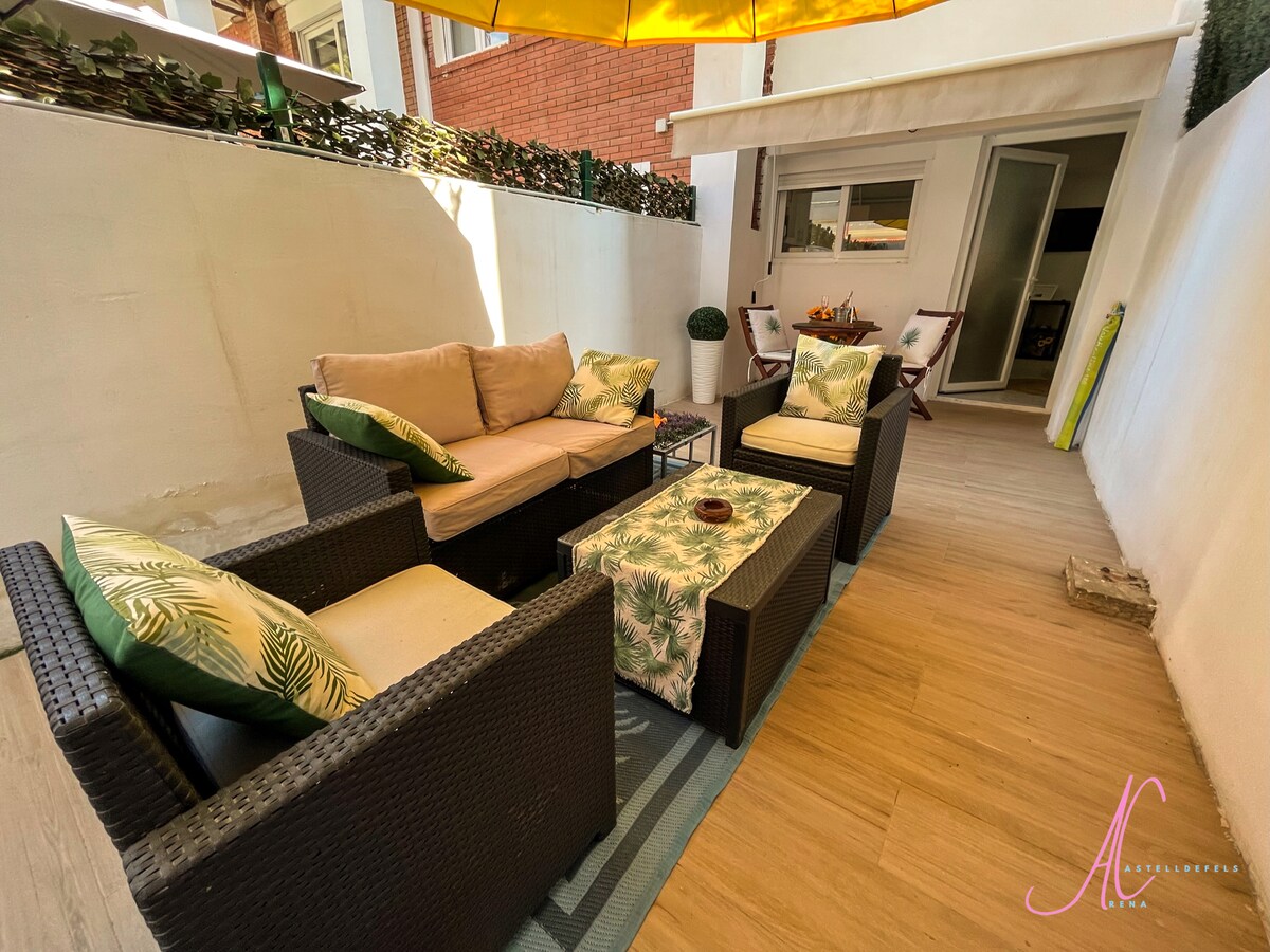 A shaded outdoor seating area features comfortable, cushioned sofas adorned with greenery-themed pillows. A glass-topped table sits in the center, surrounded by chairs. Natural light filters through a canopy overhead, enhancing the inviting atmosphere of the private space.