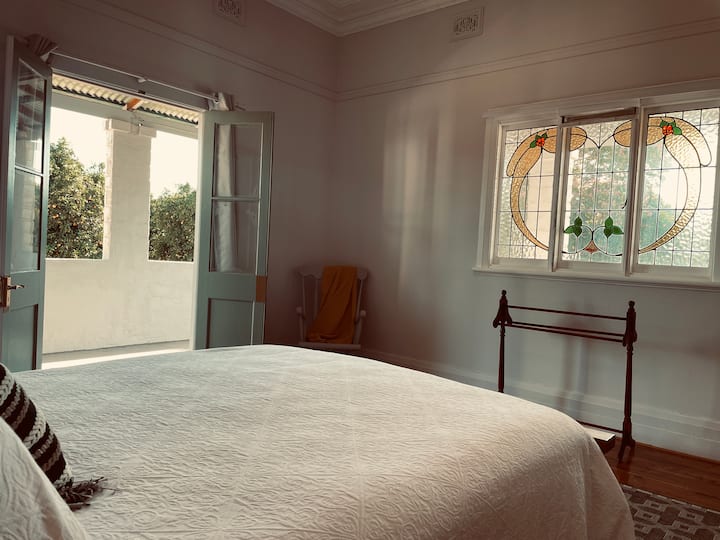 Първа спалня с витражи и френски врати, които се отварят към верандата.
