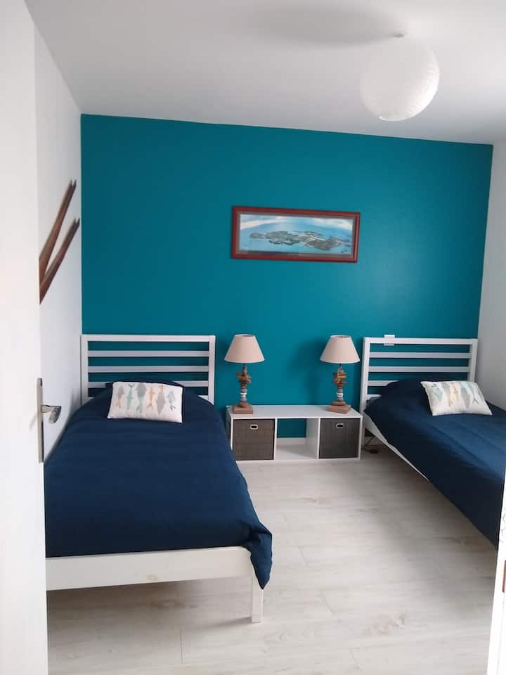 Deuxième chambre  avec ses lits individuels standards, ses oreillers et couettes ainsi qu'une commode