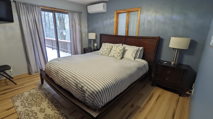 Spálňa s manželskou posteľou veľkosti King na 1. poschodí s posuvnými dverami na terasu a televízorom Roku