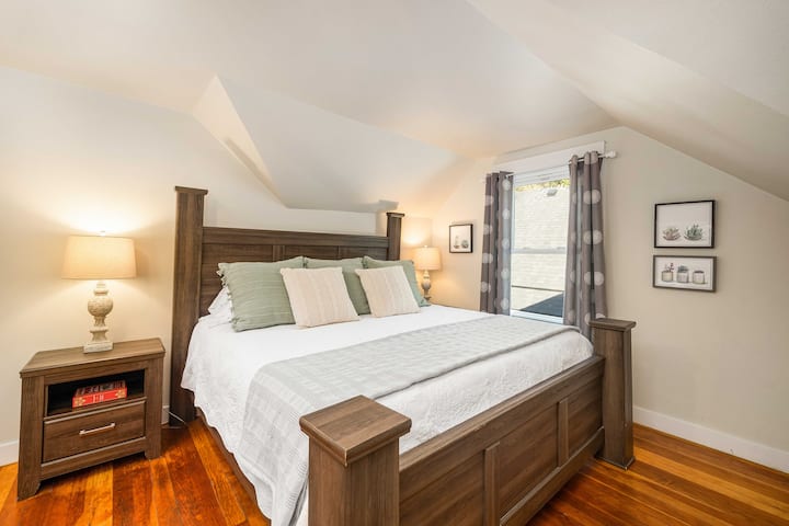 Bedroom 1 with king bed and warm wood floors.