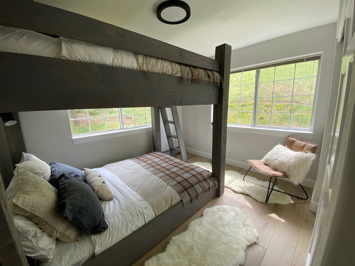 מיטות קווין סייז עם מצעים חדשים של Pottery Barn, כריות ושמיכות פוך.  שמיכות טרטן אנגליות ושטיחים מעור כבש מוסיפים לנעימות של החדר הזה.  