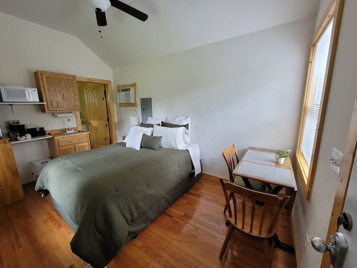 Krevet sa stolom i stolicama ispod prozora na šljunčanom parkiralištu.