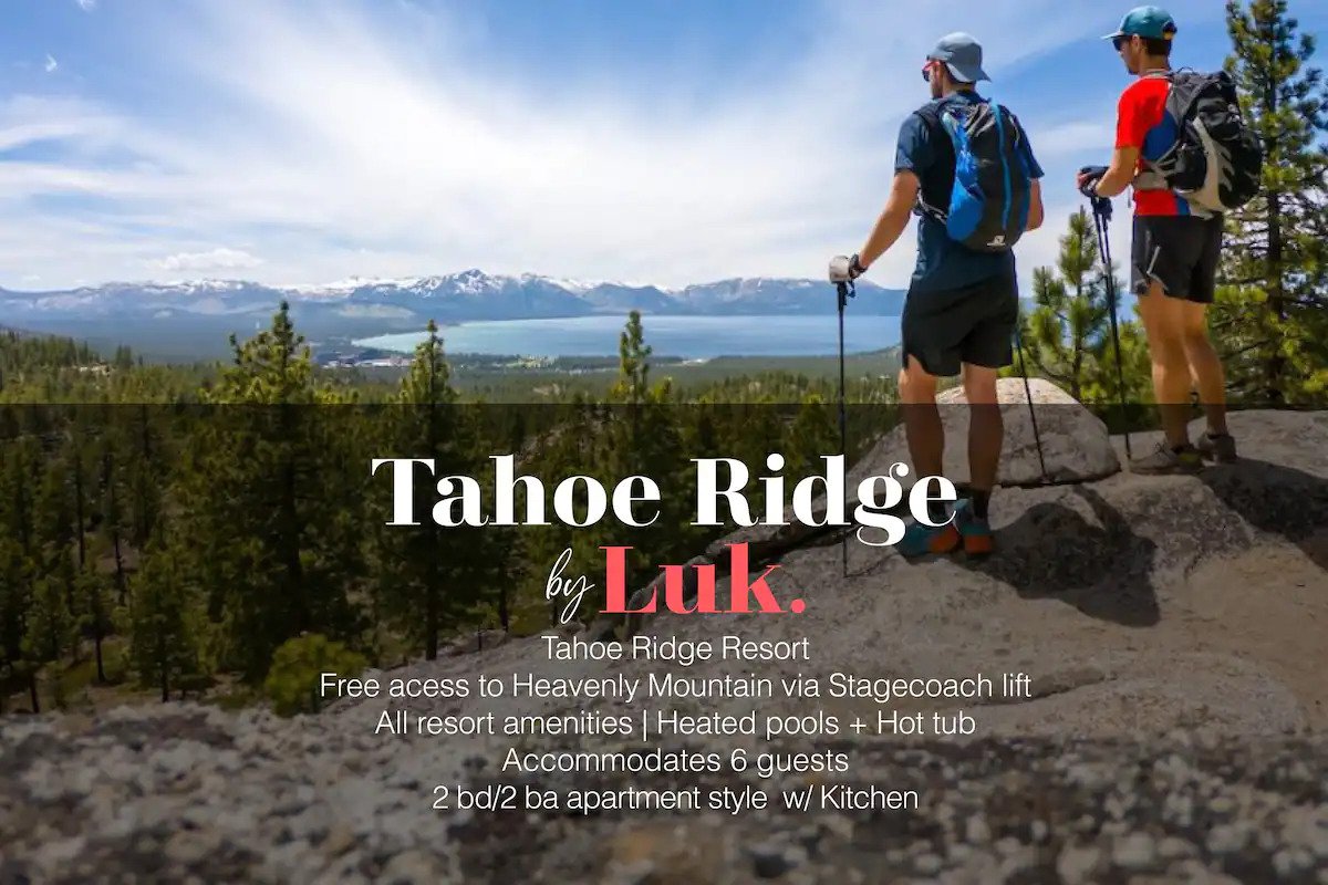 Two individuals stand on a rocky outcrop overlooking a scenic expanse of mountains and a lake. Towering pine trees frame the area, with distant peaks under a clear blue sky. Accessible amenities include heated pools and a hot tub, highlighting the resort's offerings.