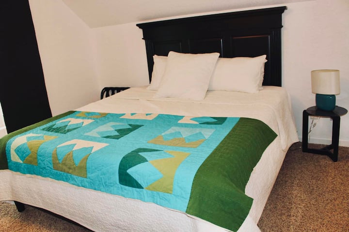 第一间卧室在楼梯路左侧，配加大双人床新床垫2023和枕套。 房间还包括行李架、衣柜、椅子和衣物代客泊车。 