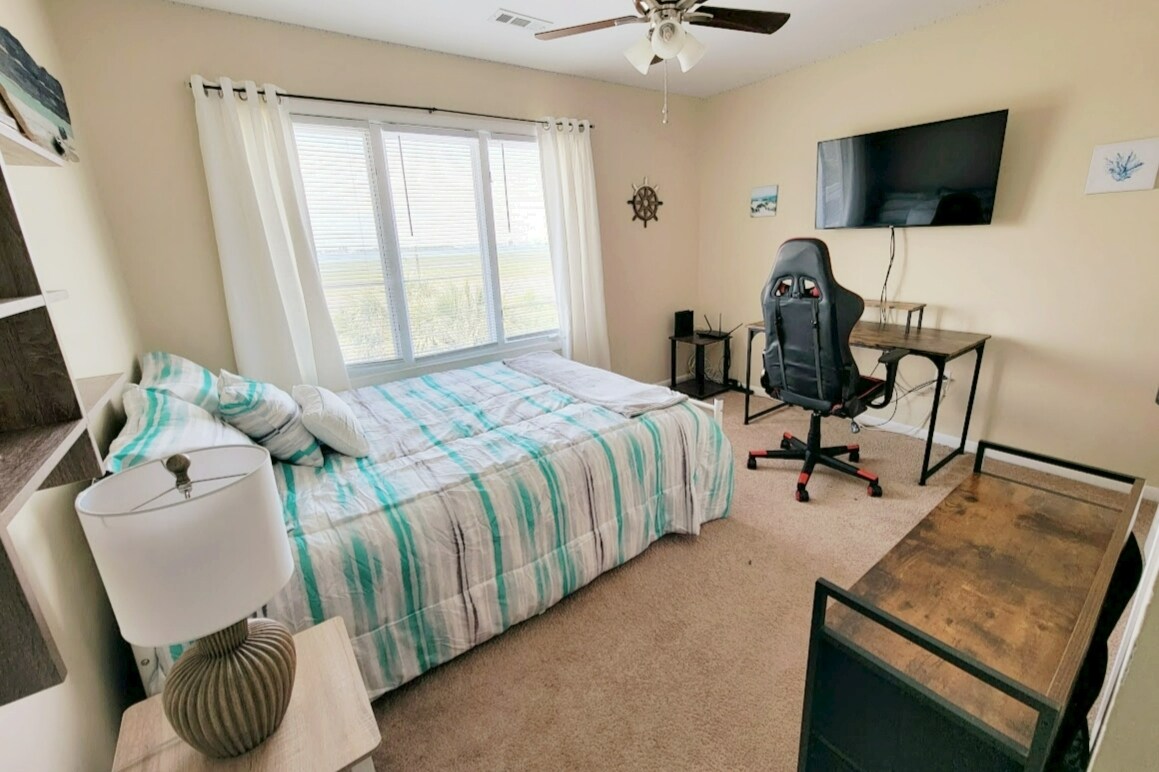 Pumzika katika chumba hiki cha kulala cha kwanza cha wageni kilicho na feni mpya ya dari, televisheni kubwa kwa ajili ya michezo ya kubahatisha au kutazama filamu uipendayo na mandhari ya ufukweni. Kioo kikubwa juu ya kabati la kujipambia upande wa kulia pamoja na kabati la Wi-Fi imesimama katika chumba hiki.