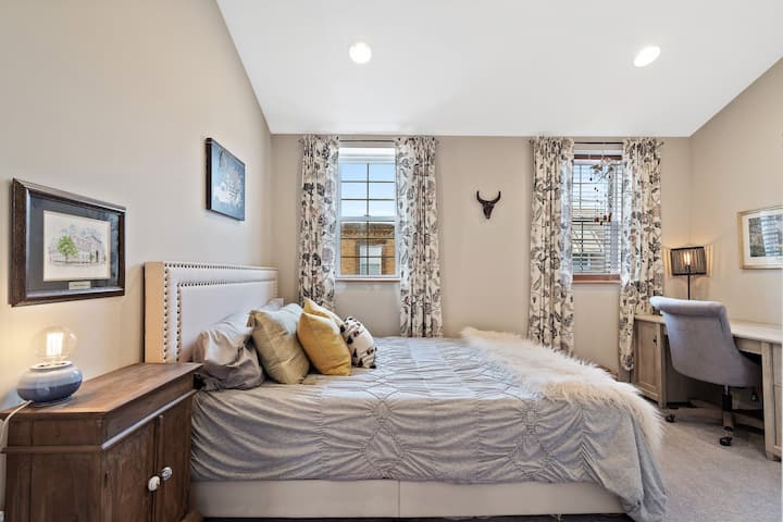 Mapumziko yenye utulivu yenye rangi laini, matandiko ya kupangusa na kuchuja mwanga wa asili kupitia mapazia maridadi.
